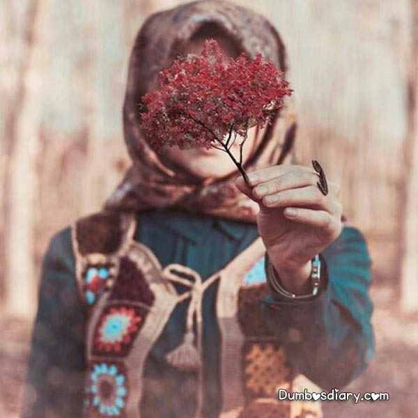 Beautiful hijabi girl hiding her face with flowers