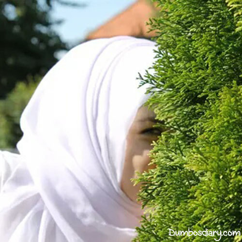 Hijabi girl hiding behind bush